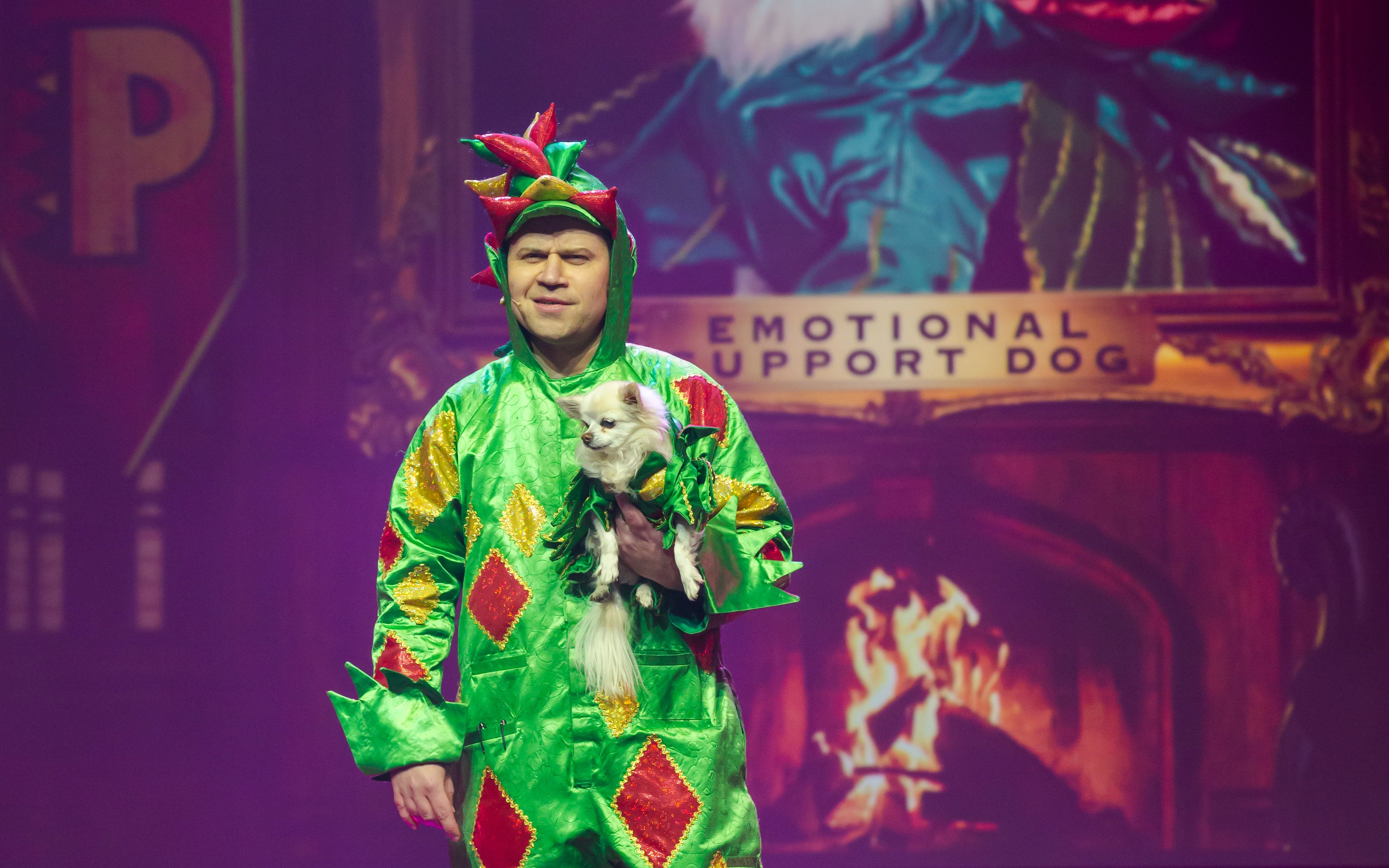Performer in dragon costume holding a small dog on stage at Piff the Magic Dragon show, Vegas.