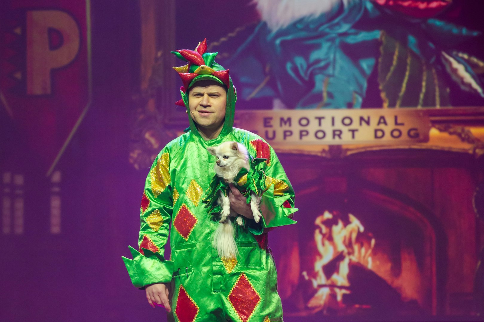 Performer in dragon costume holding a small dog on stage at Piff the Magic Dragon show, Vegas.
