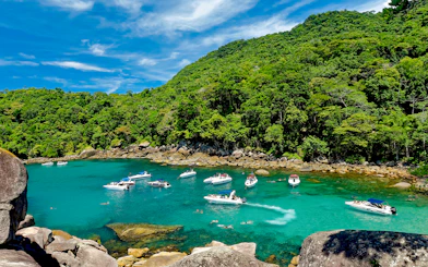 Boats and swimmers in a turquoise bay surrounded by lush forest on Ilha Grande, Rio de Janeiro.