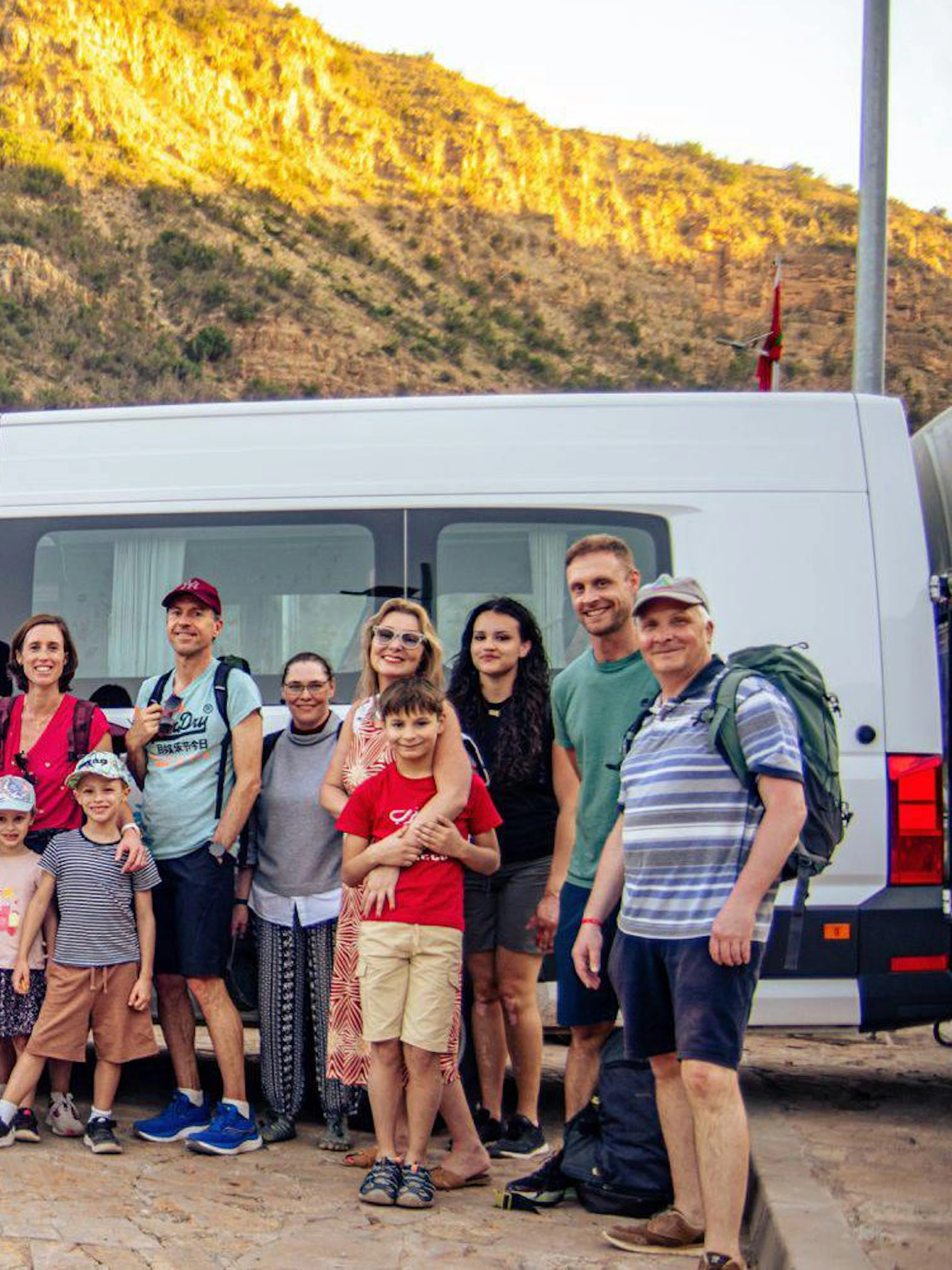 Group of tourists in front of a van at Paradise Valley with a mountain backdrop.