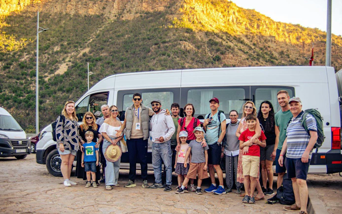Group of tourists in front of a van at Paradise Valley with a mountain backdrop.