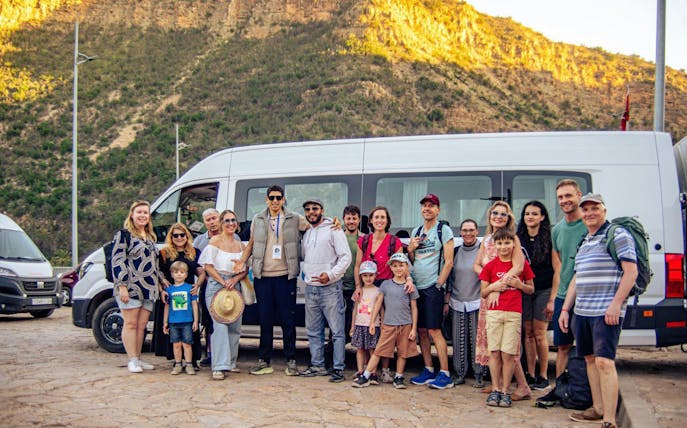 Group of tourists in front of a van at Paradise Valley with a mountain backdrop.