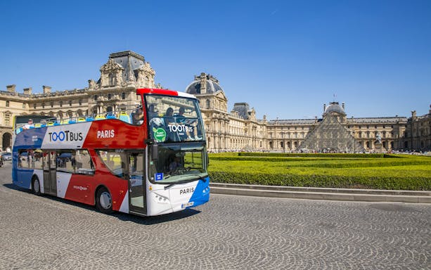 Tootbus Paris tour bus in front of the Louvre Museum.