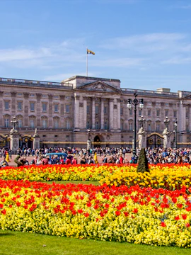 Buckingham Palace with colorful flower gardens and visitors in London.