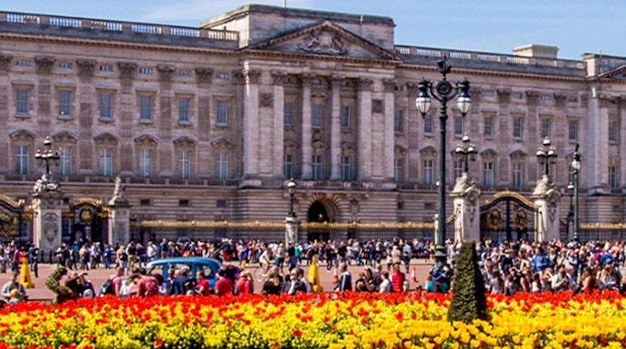 Buckingham Palace with colorful flower gardens and visitors in London.