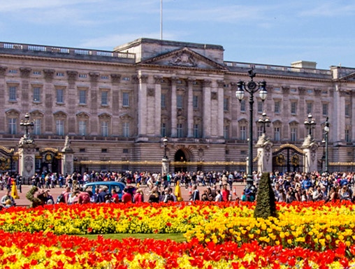 Buckingham Palace with colorful flower gardens and visitors in London.