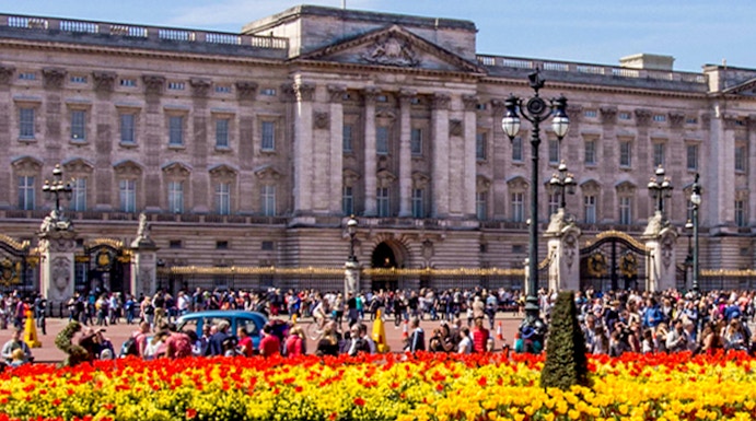 Buckingham Palace with colorful flower gardens and visitors in London.