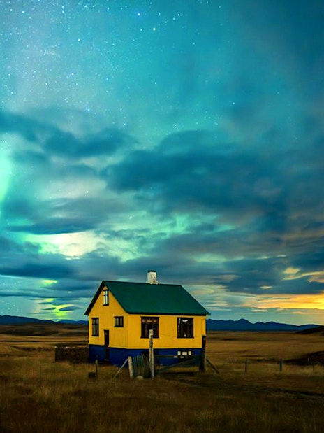 Northern lights over a rural house during Premium Northern Lights Super Jeep Tour.
