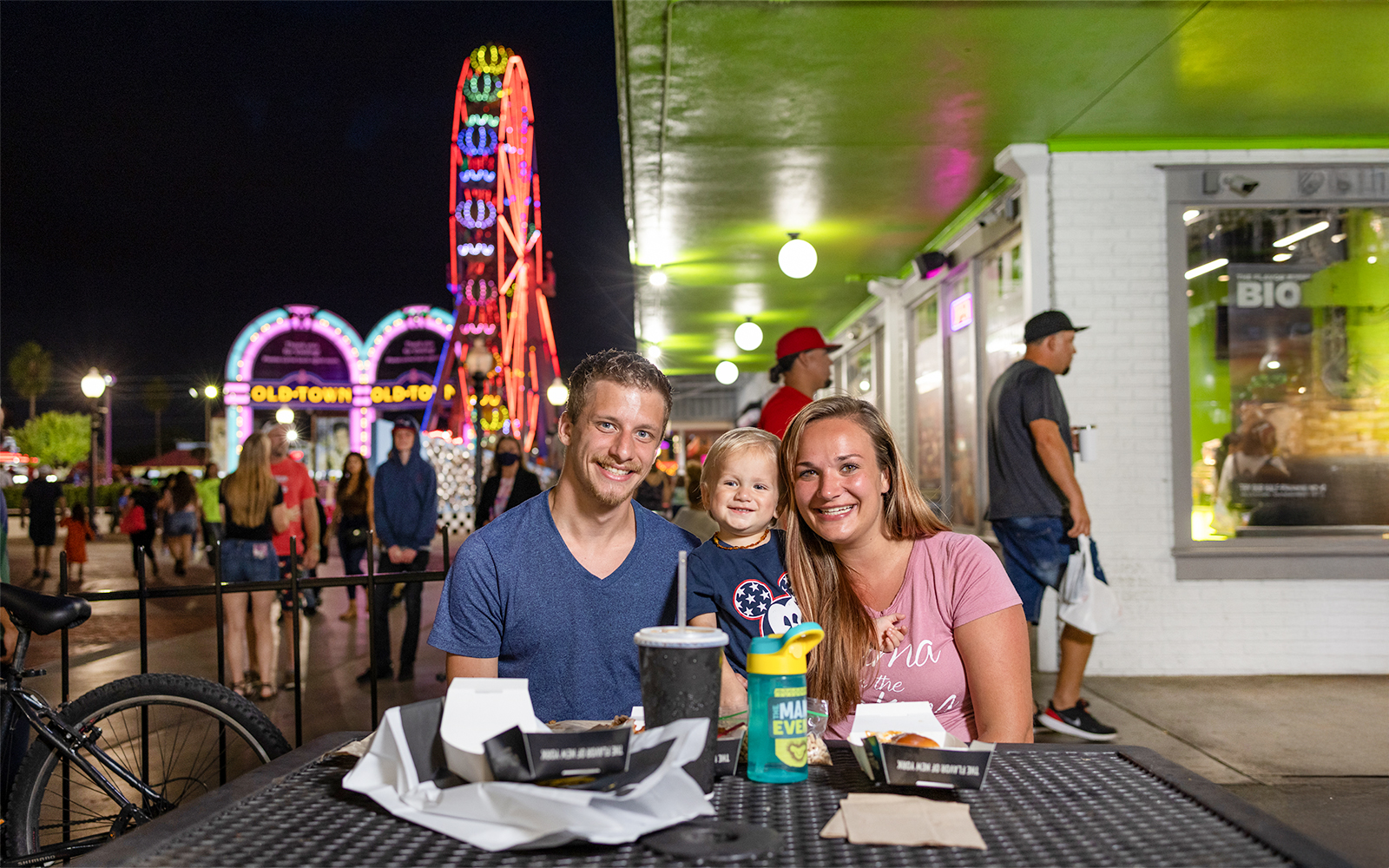 Guests dining at Old Town, Orlando with neon Ferris wheel in the background.