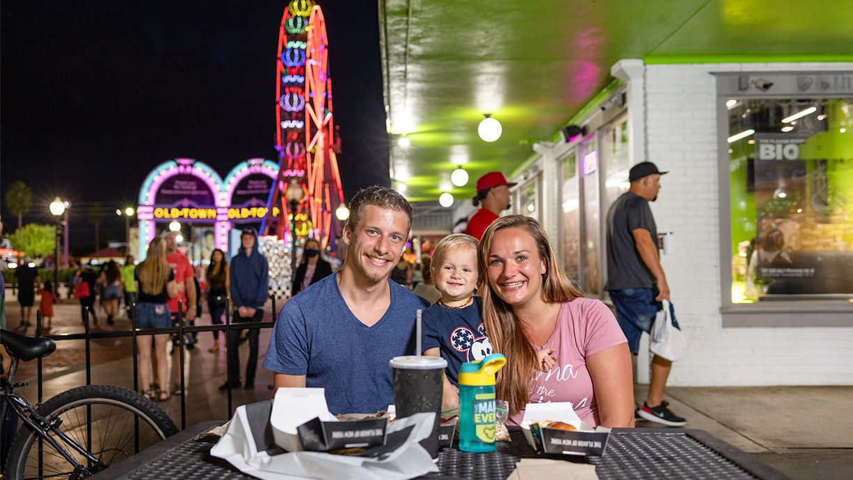Guests dining at Old Town, Orlando with neon Ferris wheel in the background.