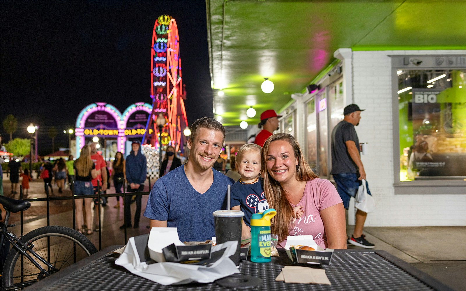 Guests dining at Old Town, Orlando with neon Ferris wheel in the background.