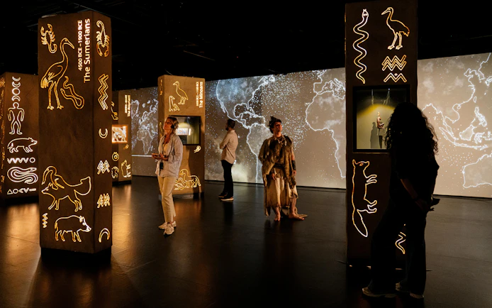 Visitors exploring illuminated ancient symbols at the London Timewalk Exhibition.