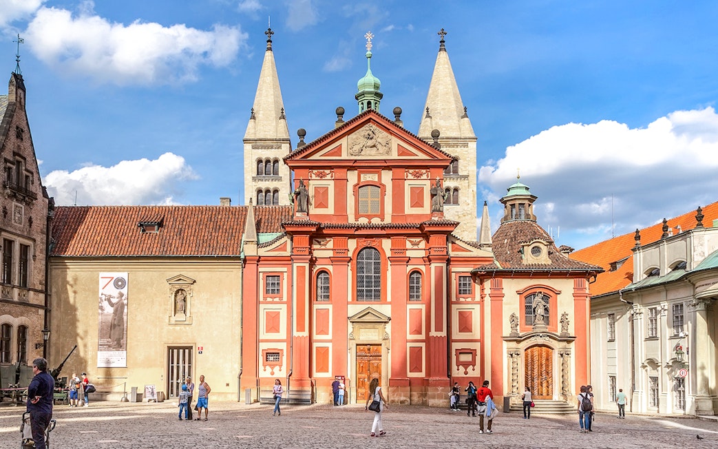 Basilica of St George exterior with tourists in Prague courtyard.