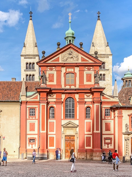 Basilica of St George exterior with tourists in Prague courtyard.