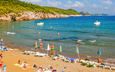 Tourists enjoying Sunj Beach on Lopud Island with boats in the Adriatic Sea.
