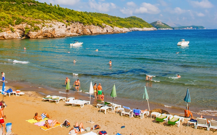 Tourists enjoying Sunj Beach on Lopud Island with boats in the Adriatic Sea.