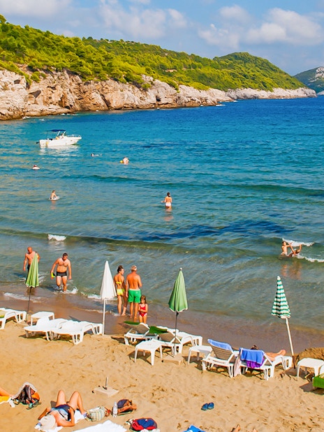 Tourists enjoying Sunj Beach on Lopud Island with boats in the Adriatic Sea.