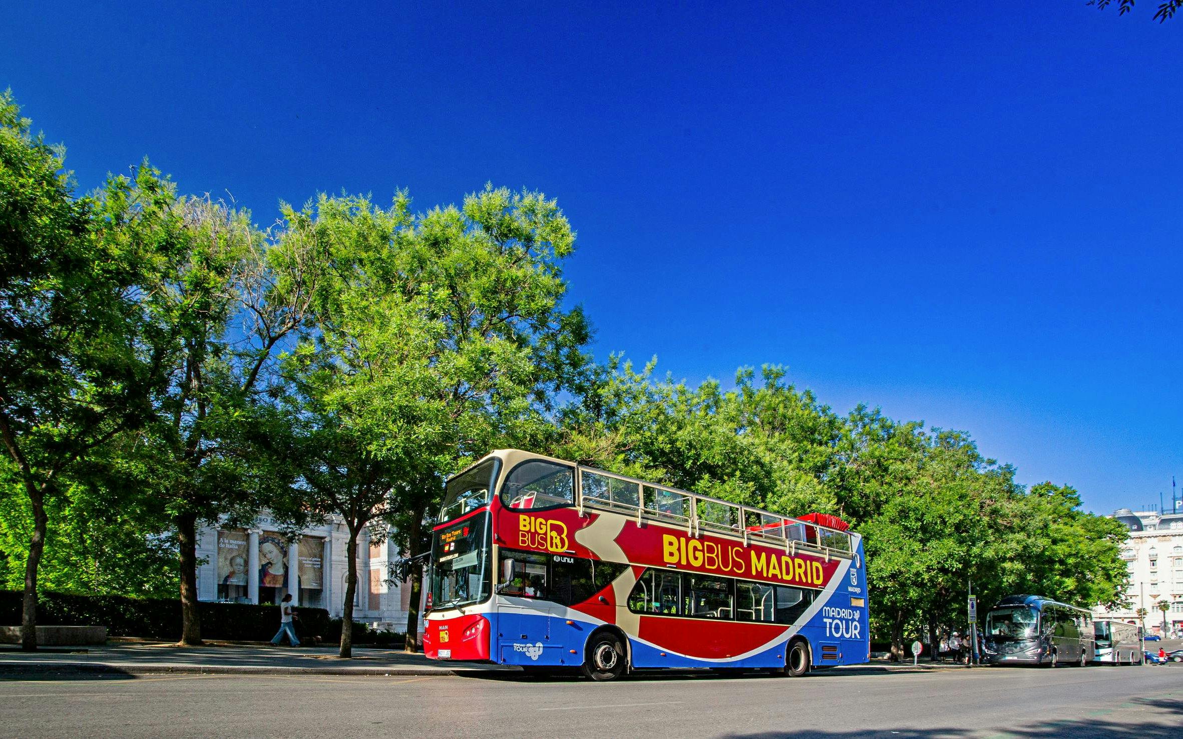 Open-top Big Bus Madrid tour bus on a sunny street with trees and buildings.