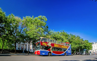 Open-top Big Bus Madrid tour bus on a sunny street with trees and buildings.