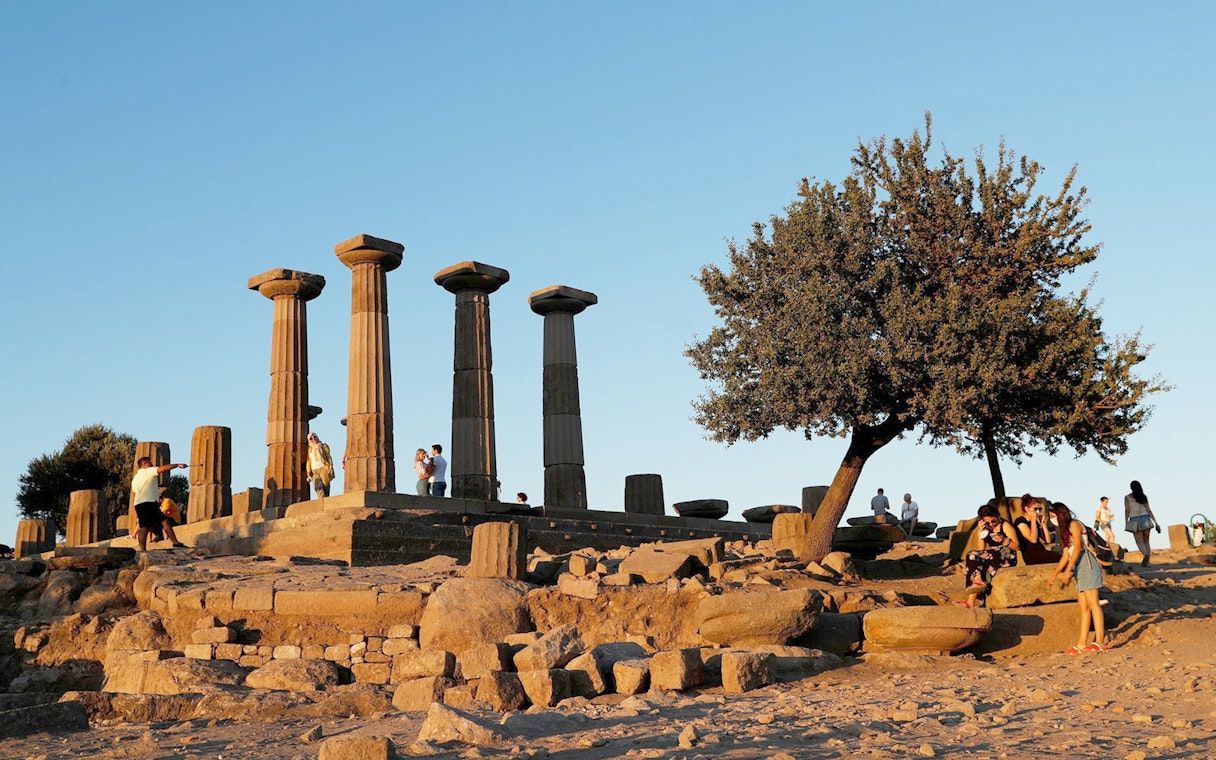 Ancient ruins with columns and tourists at sunset during Full-Day Troy Tour from Istanbul.