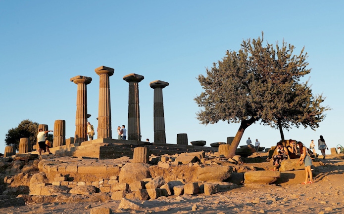 Ancient ruins with columns and tourists at sunset during Full-Day Troy Tour from Istanbul.
