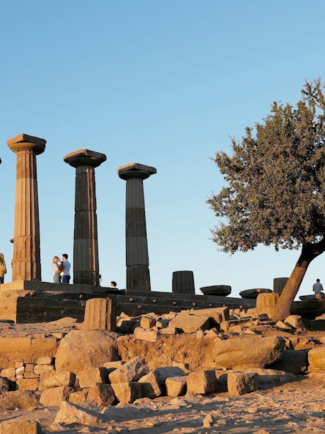 Ancient ruins with columns and tourists at sunset during Full-Day Troy Tour from Istanbul.