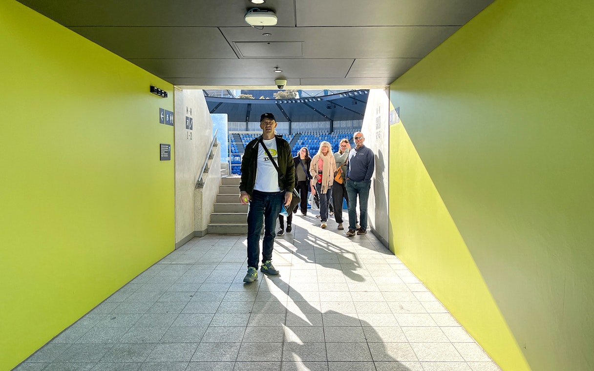 Group walking through Melbourne Park tennis stadium tunnel.