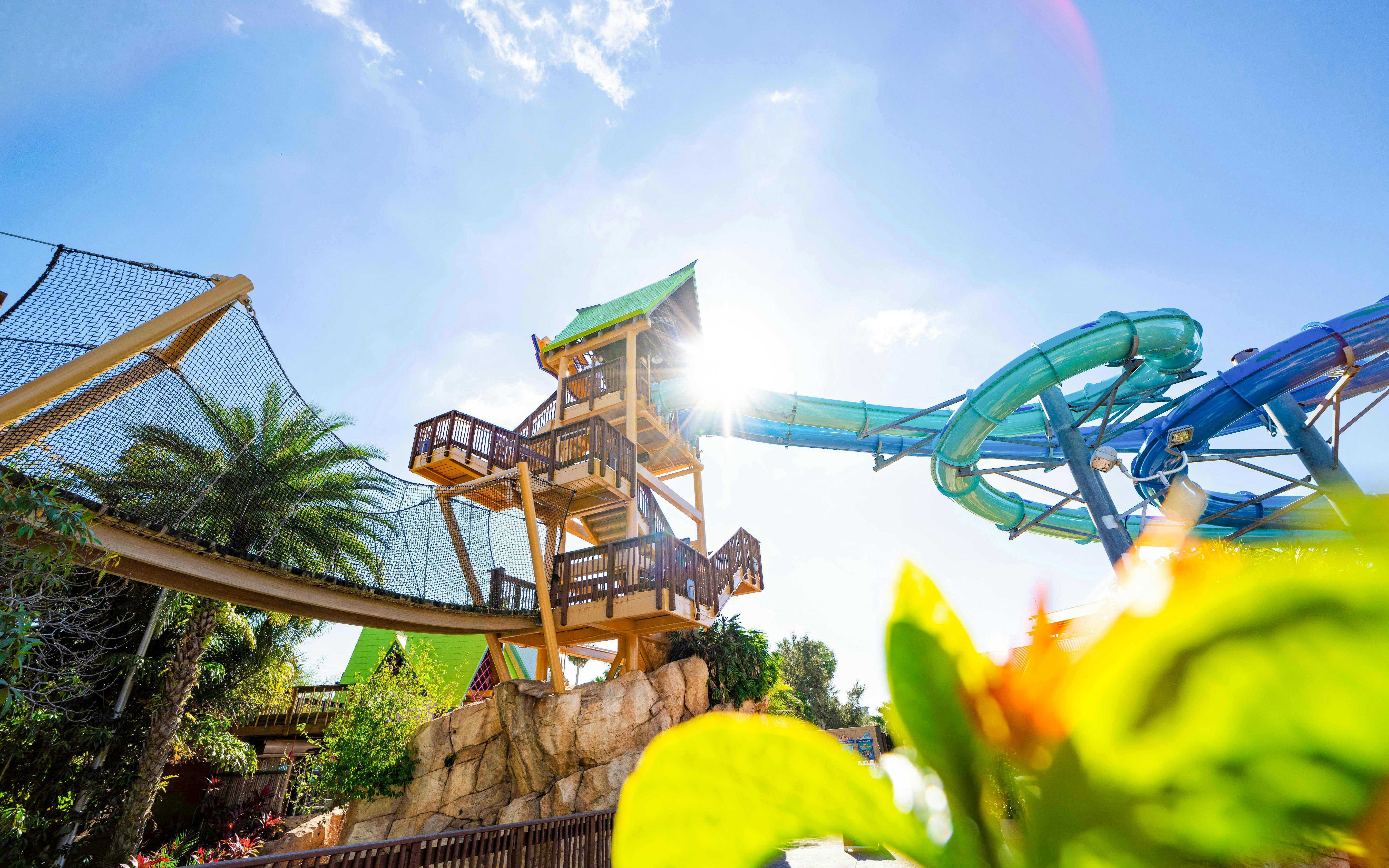 Aquatica Orlando water slide tower with bright sun and tropical plants.