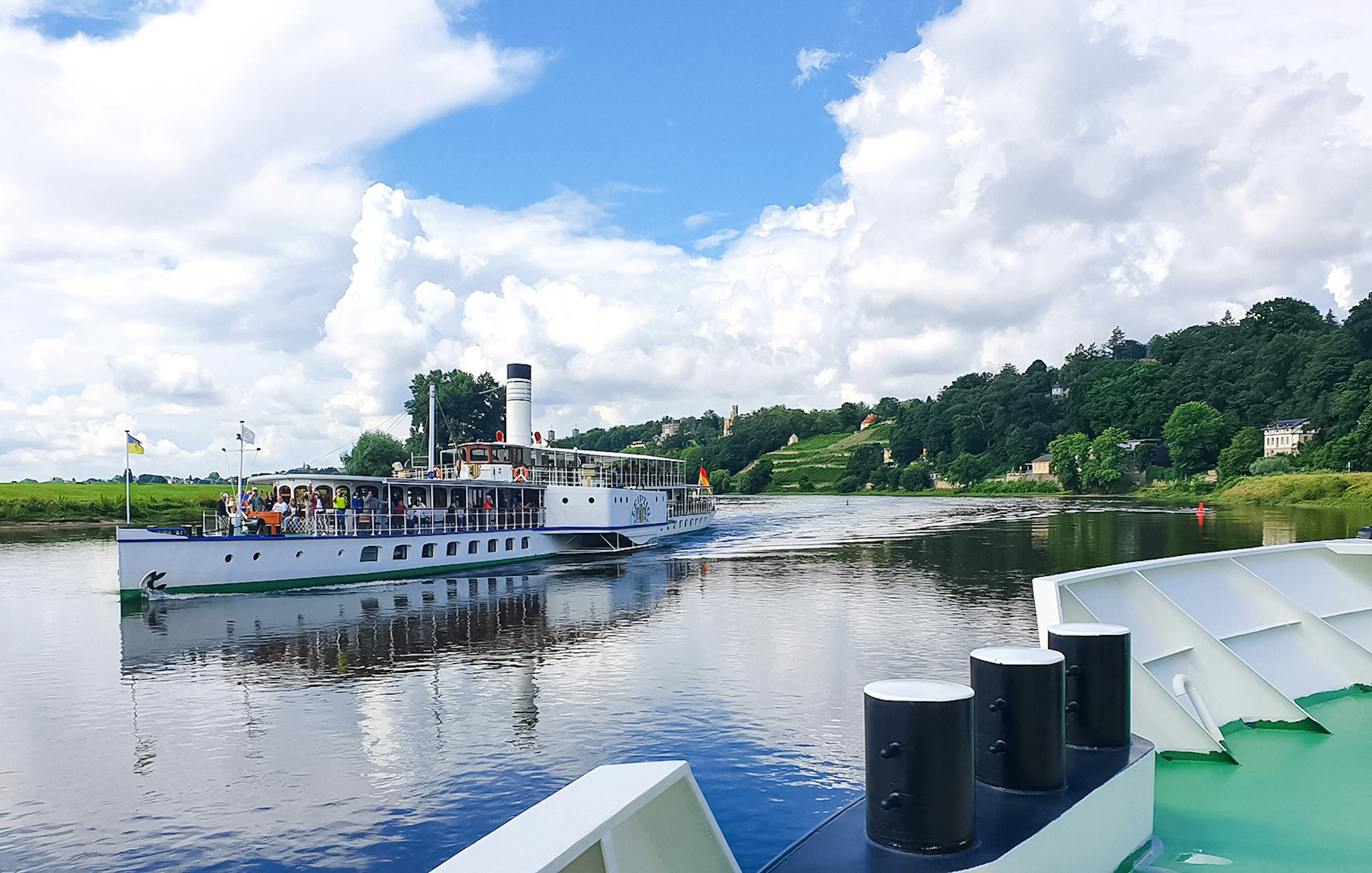 Paddle steamer cruising on the Elbe River near Dresden with scenic views.