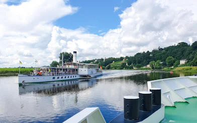 Paddle steamer cruising on the Elbe River near Dresden with scenic views.