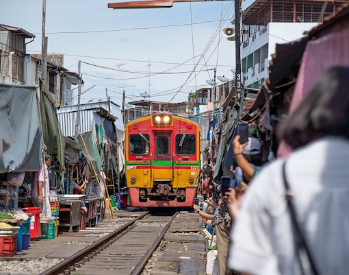 A colorful train passes through Maeklong Railway Market