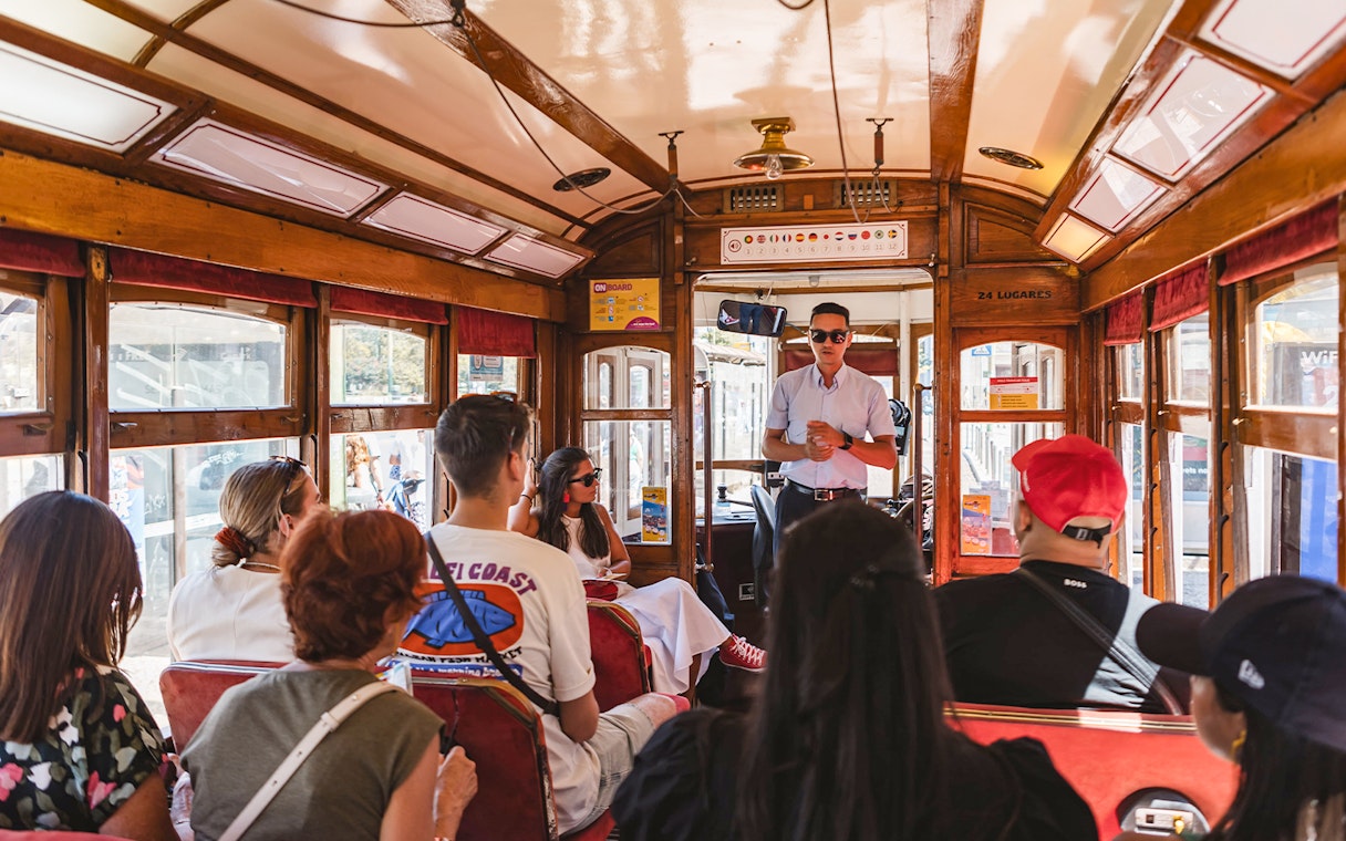 Tour guide speaking to passengers on a Lisbon tram during a hop-on hop-off tour.