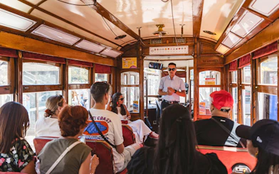 Tour guide speaking to passengers on a Lisbon tram during a hop-on hop-off tour.