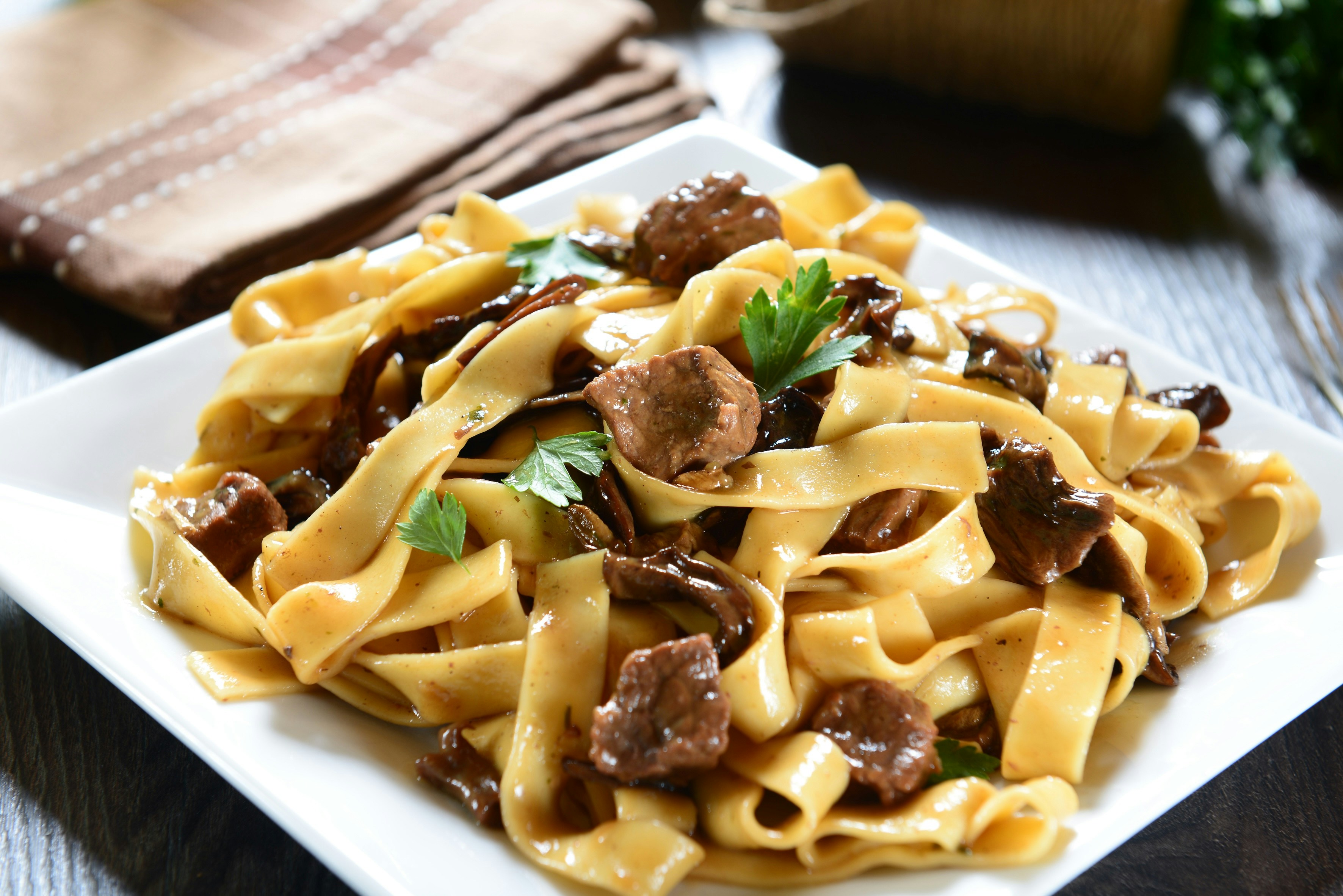 Freshly made tagliatelle pasta on a wooden board, Italy.