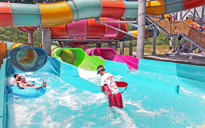 Visitors enjoying water slides at Six Flags Over Georgia with a lifeguard nearby.