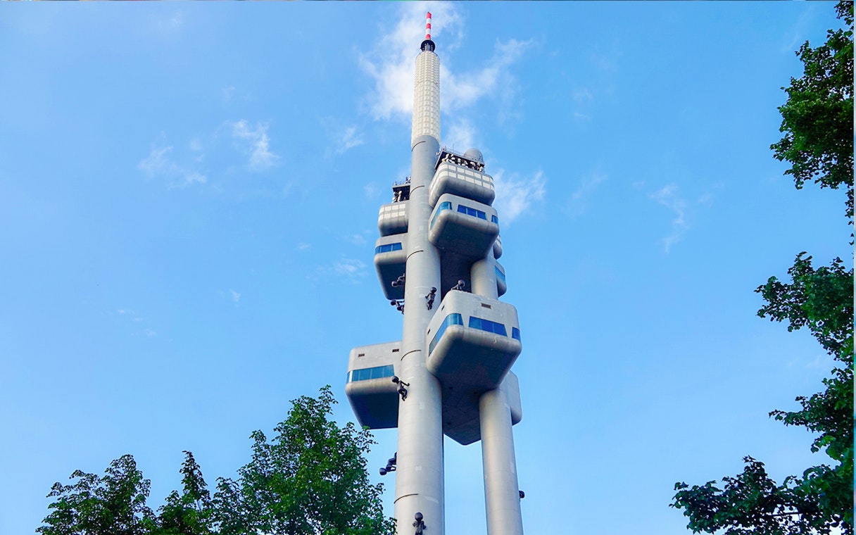 Žižkov Television Tower in Prague with sculptures and observation decks against blue sky.