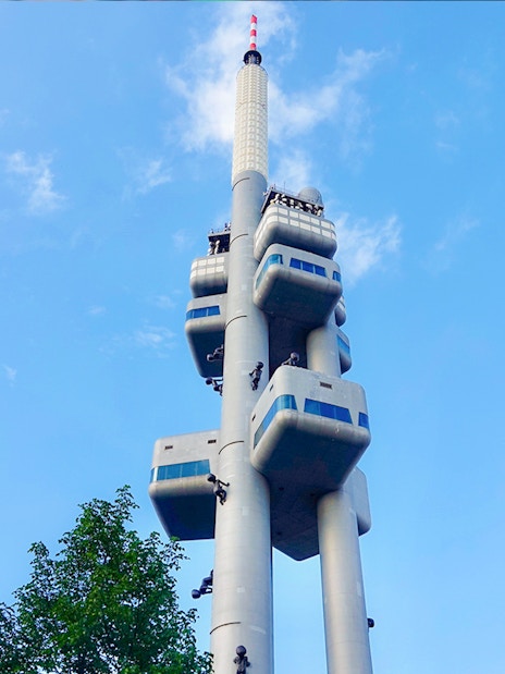 Žižkov Television Tower in Prague with sculptures and observation decks against blue sky.