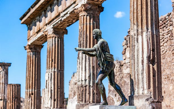 Ancient statue and columns in Pompeii, Italy, part of Naples City Pass tour.