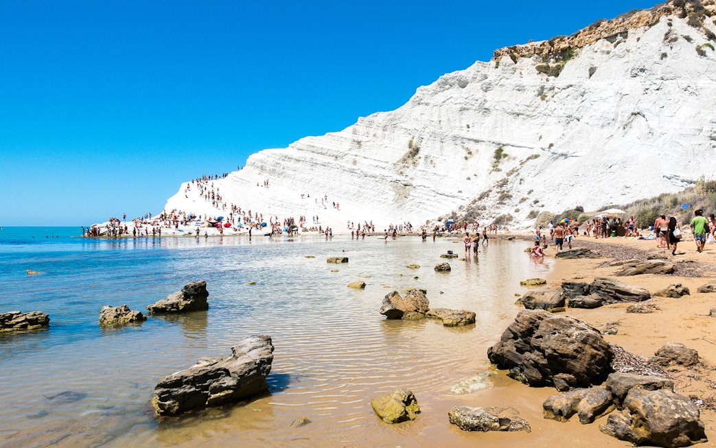 Visitors exploring the white cliffs of the Stair of the Turks in Agrigento, Sicily.