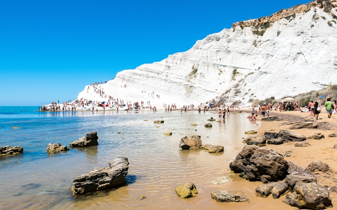 Visitors exploring the white cliffs of the Stair of the Turks in Agrigento, Sicily.