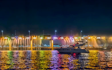 Yacht on Han River at night with colorful bridge lights in Seoul.