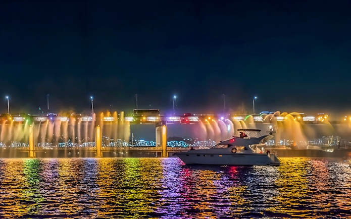 Yacht on Han River at night with colorful bridge lights in Seoul.