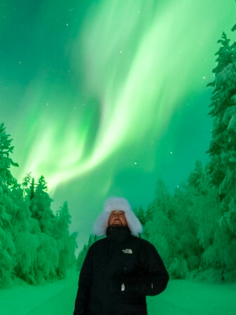 Guests viewing Northern Lights on snowy forest tour.