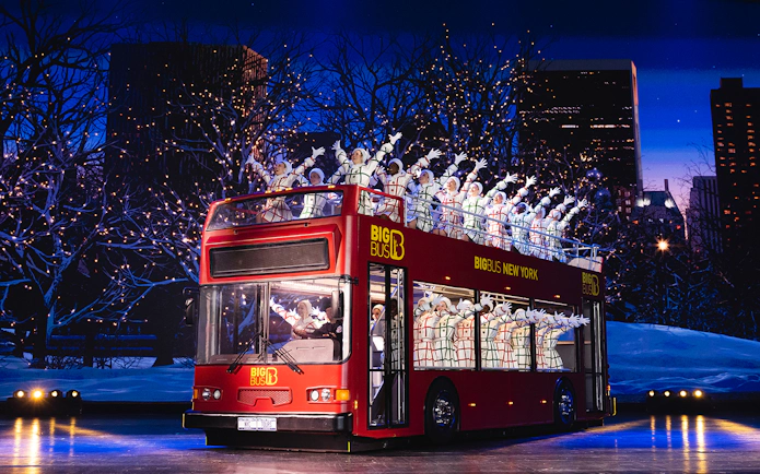 Radio City Rockettes performing on a double-decker bus in New York City during Christmas.
