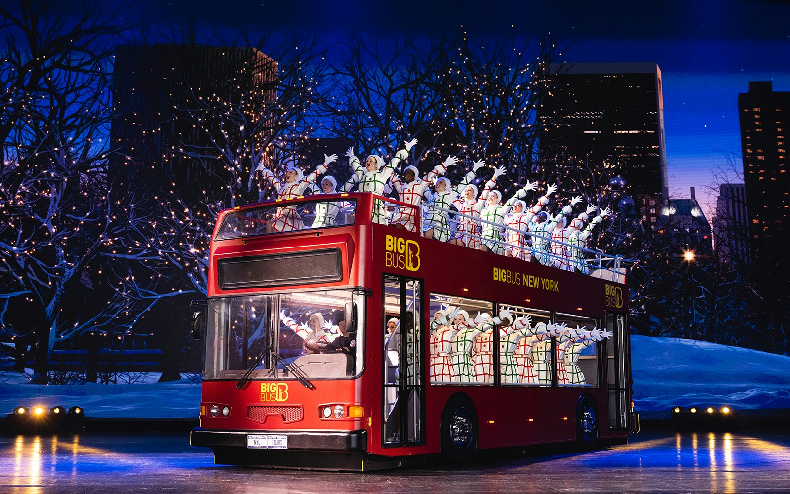 Radio City Rockettes performing on a double-decker bus in New York City during Christmas.