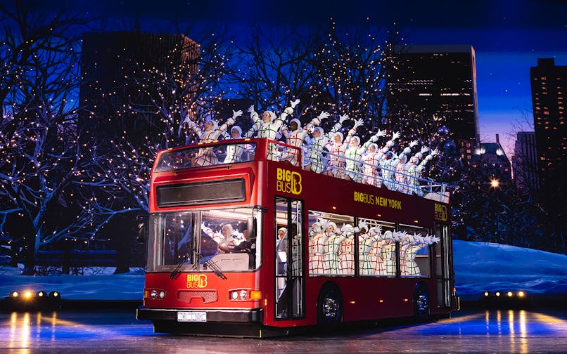 Radio City Rockettes performing on a double-decker bus in New York City during Christmas.