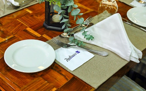 Elegant table setting on Dubai Marina Dhow Cruise with Radisson napkin.