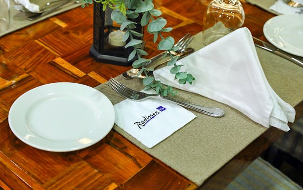 Elegant table setting on Dubai Marina Dhow Cruise with Radisson napkin.