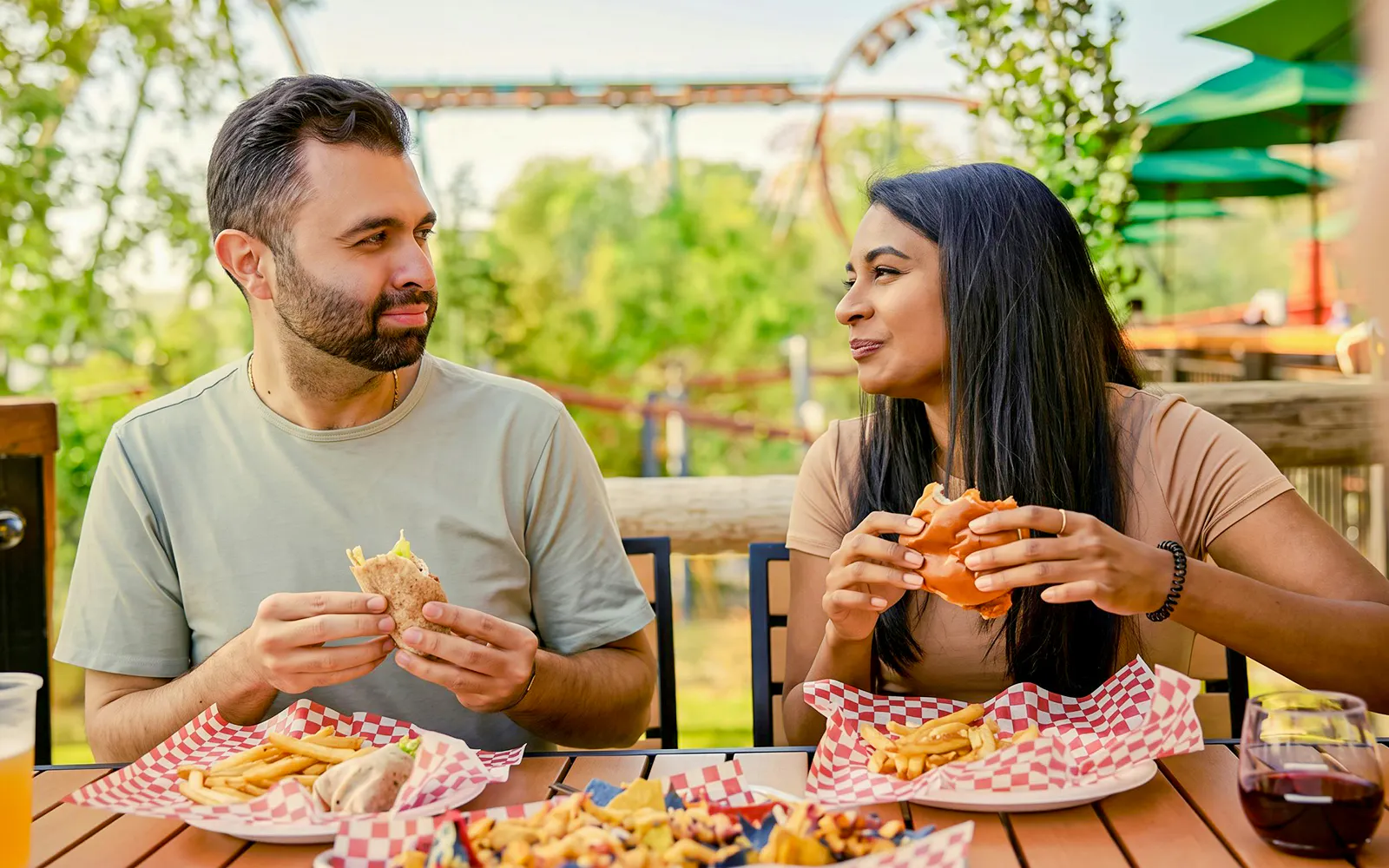 Couple enjoying burgers and fries at an outdoor dining area in Kings Island.