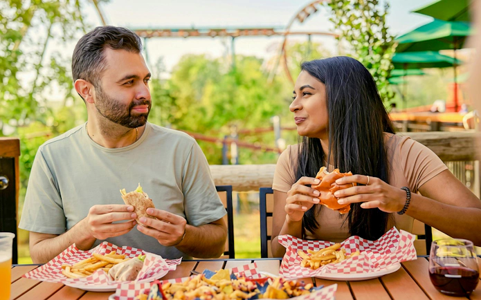 Couple enjoying burgers and fries at an outdoor dining area in Kings Island.
